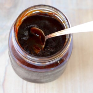 A jar of barbecue sauce with a spoon inserted.