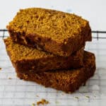 Three slices of gluten free pumpkin loaf stacked on a plate.
