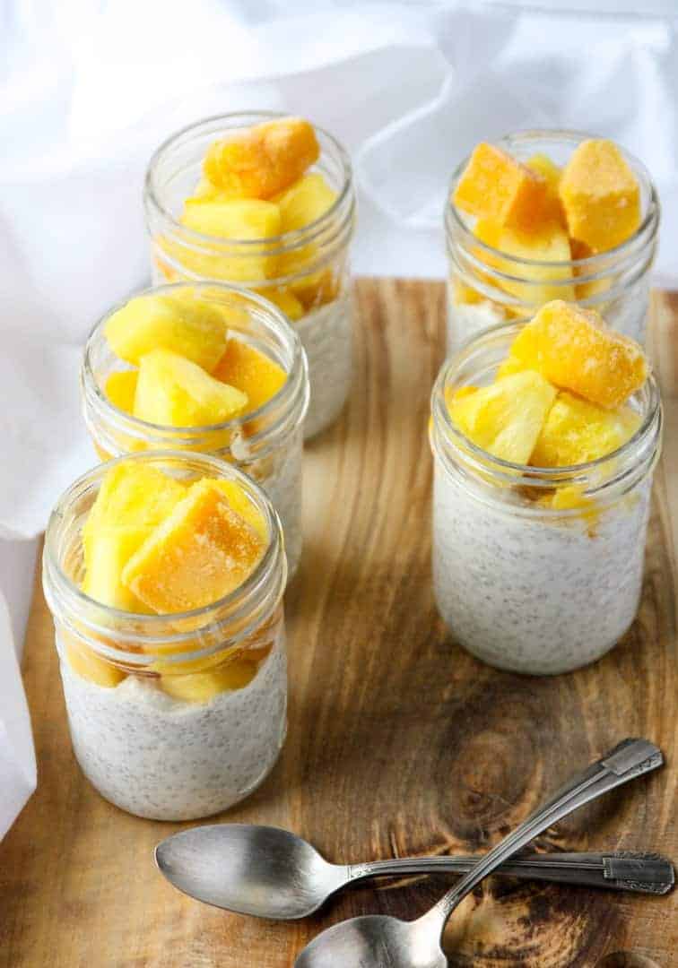 Four glass jars filled with pudding and fruit