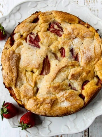 A French strawberry cake, garnished with strawberries, on a cake plate.