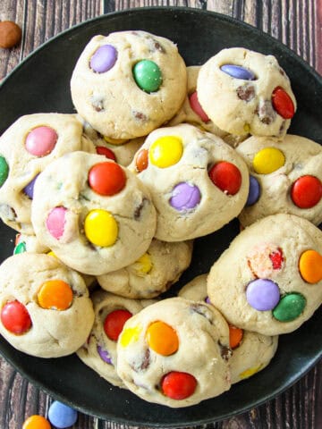 Smarties cookies on a black plate.