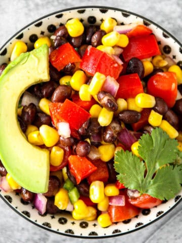 Fiesta salad topped with avocado slices, in a black and white bowl.