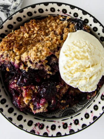 Gluten-free blueberry crisp in a black and white bowl.